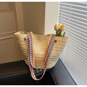 Detailed straw tote bag texture with colorful ethnic strap on a leather sofa