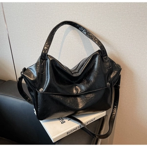 Close-up of black oil-wax leather handbag with wrinkled texture on white books