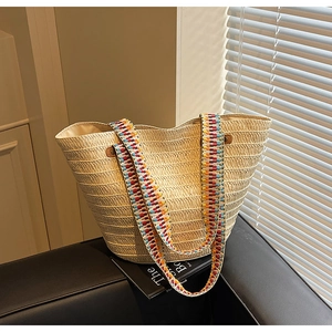 Detail of hand-woven straw tote bag with vibrant geometric patterned shoulder strap