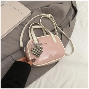 Détail du sac à main rose verni avec charme cœur argenté et bordure blanche contrastée