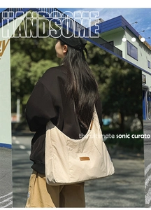 Detail of off-white canvas tote bag featuring brown leather logo and street style design