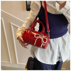 Detail of red patent leather pillow bag with pearl bow charm and heart metal pendant