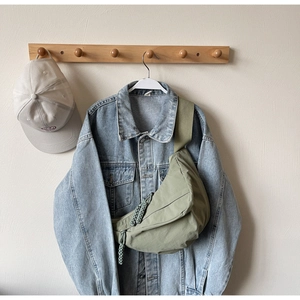 Detail of green nylon crescent bag with woven rope zipper on a denim jacket