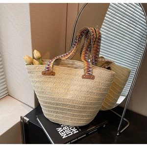 Close-up of woven straw tote bag with vibrant bohemian embroidered ribbon handles