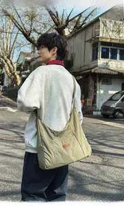 Detail view of large olive green canvas tote bag worn by male model in street style