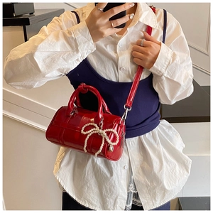 Detail of red patent leather pillow bag with pearl bow charm and gold hardware