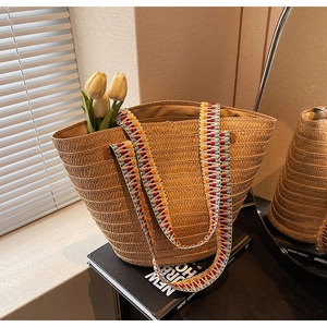 Detail of hand-woven straw tote bag with colorful striped strap and inner lining