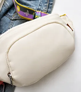 Close-up of cream white chest bag with stylish colorful butterfly strap on denim background