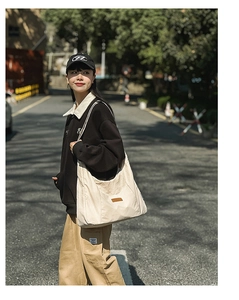 Detailed side view of beige canvas tote bag with brown leather label in street setting