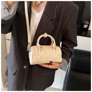 Crossbody view of mini cream pillow bag with detachable shoulder strap on model