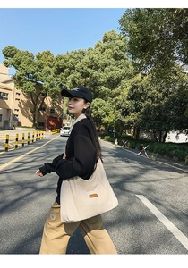 Outdoor street style showing beige canvas tote bag with brown leather tag for casual wear