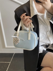 Sac bandoulière bleu ciel brillant avec liseré blanc et breloque en forme de cœur argenté