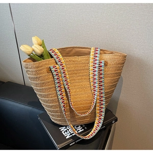 Detail of hand-woven straw tote bag with colorful ethnic style woven shoulder strap
