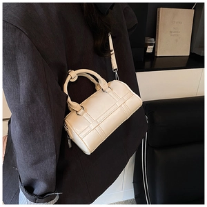 Detail of a beige pillow handbag with cross-stitch pattern and adjustable strap