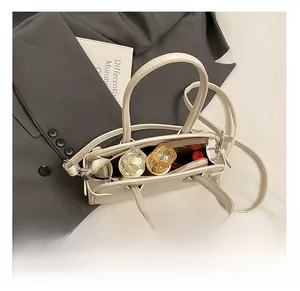 Détail montrant la capacité interne du sac Boston crème avec téléphone et parfum