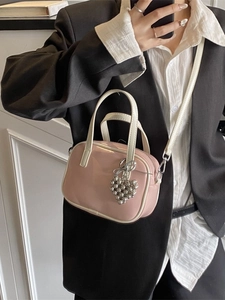 Mini sac à main rose avec breloque cœur et bord blanc, porté avec un blazer noir