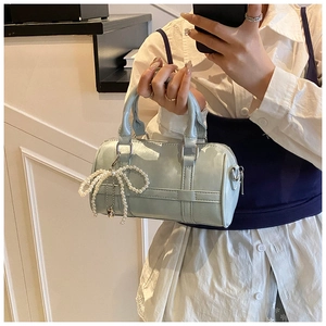 Close-up of light blue cylindrical Boston bag with decorative pearl bow charm