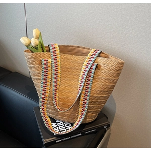 Detail of straw woven bucket bag with colorful ethnic embroidered shoulder strap and tulips
