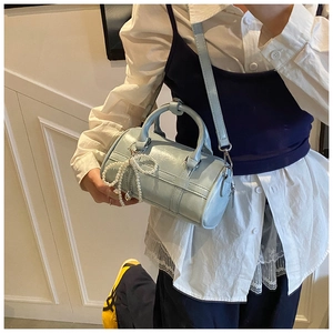 Detail of light blue pillow bag with pearl bow charm and silver hardware shown on model