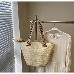 Detail of handwoven straw tote featuring bohemian geometric patterns on the handle straps