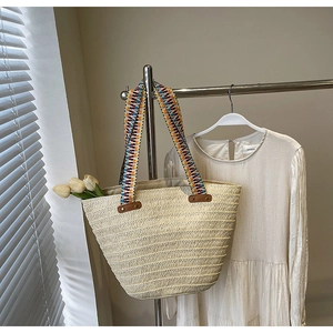Detail of woven straw tote bag with geometric pattern straps and rivet reinforcement