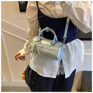 Detail of light blue pillow bag with glossy finish and pearl bow charm accessory