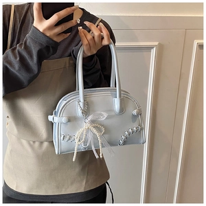 Détail d'un sac bowling bleu clair avec bordure en dentelle et pendentif noeud perlé