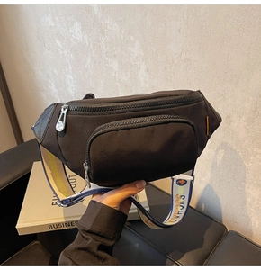 Detail view of black nylon crossbody bag with double zippers and jacquard woven strap
