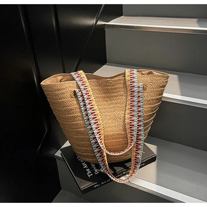 Detailed close-up of straw woven tote bag featuring ethnic colorful geometric shoulder straps