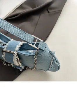 Detailed close-up of light blue denim shoulder bag with frayed edges and silver hardware