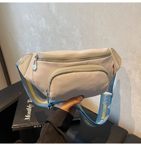 Detail of off-white nylon chest bag featuring dual zippers and woven adjustable strap