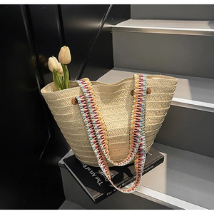 Detail of cream straw tote bag with colorful bohemian woven strap and decorative tulips