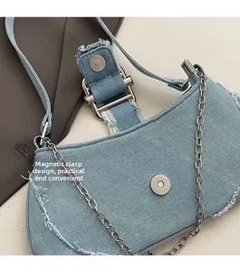 Detail of light blue denim shoulder bag featuring magnetic buckle and silver metal chain