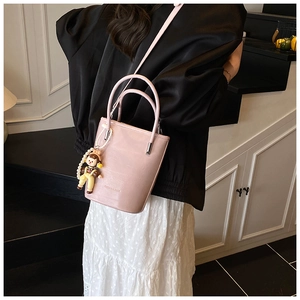 Detail van roze emmertas met parel cartoon hanger en schouderband gedragen door model