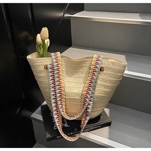 Detail of hand-woven straw tote bag with colorful ethnic patterned shoulder strap