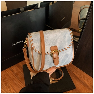 Details einer blauen Denim-Handtasche mit braunen Lederwebkanten und goldener Schnalle