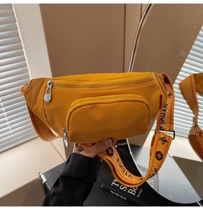 Detail of yellow nylon chest bag with patterned strap and zippered front pocket storage