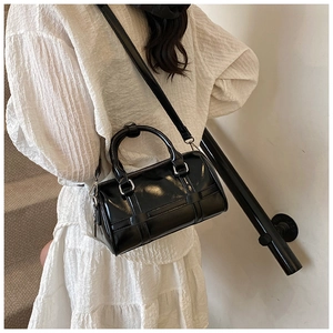 Detail of black patent leather pillow bag with silver hardware on a person