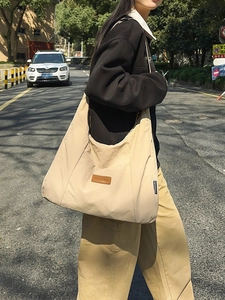 Detail showing high-density beige nylon texture and leather logo on large tote bag