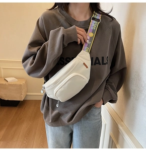 Detailed view of white nylon waist bag with colorful woven strap and front zip pocket