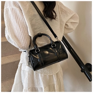 Close-up of black glossy pillow bag with silver hardware and adjustable shoulder strap