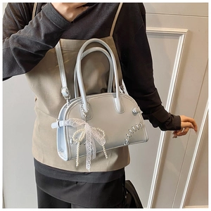 Détail du sac à bandoulière bleu clair avec nœud en dentelle blanche et perles