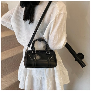 Close-up of a black glossy Boston bag with cross-strap details and adjustable shoulder strap
