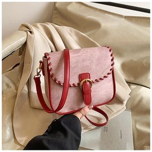 Detailansicht der rosa matten Handtasche mit roter Lederflechtung und Goldschnalle