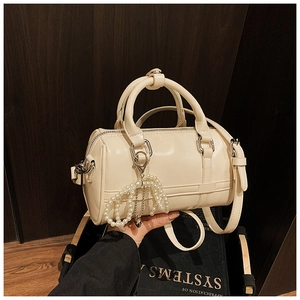 Detail of cream white boston bag with faux leather finish and pearl charm handle