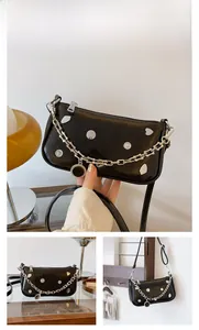 Detail of black crescent shoulder bag with silver heart studs and chunky metal chain