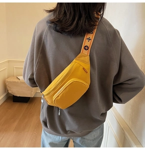Detail showing bright yellow nylon crossbody bag with printed wide shoulder strap on model