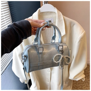 Light blue Boston pillow bag detail featuring a pearl bow chain and silver zipper