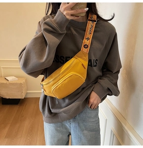 Mirror selfie showing a yellow nylon chest bag with logo strap and zipper pockets