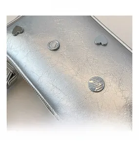 Close-up of silver crescent bag with cracked leather texture and heart-shaped metal studs